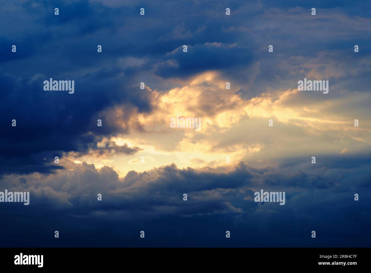 Dark storm clouds with breaking sun rays in the evening sunset sky ...
