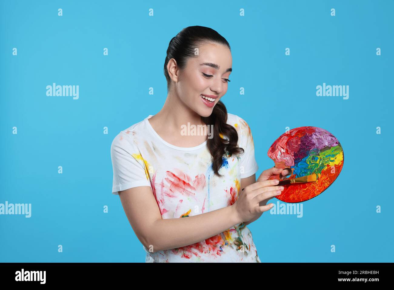 Woman with painting tools on light blue background. Young artist Stock ...