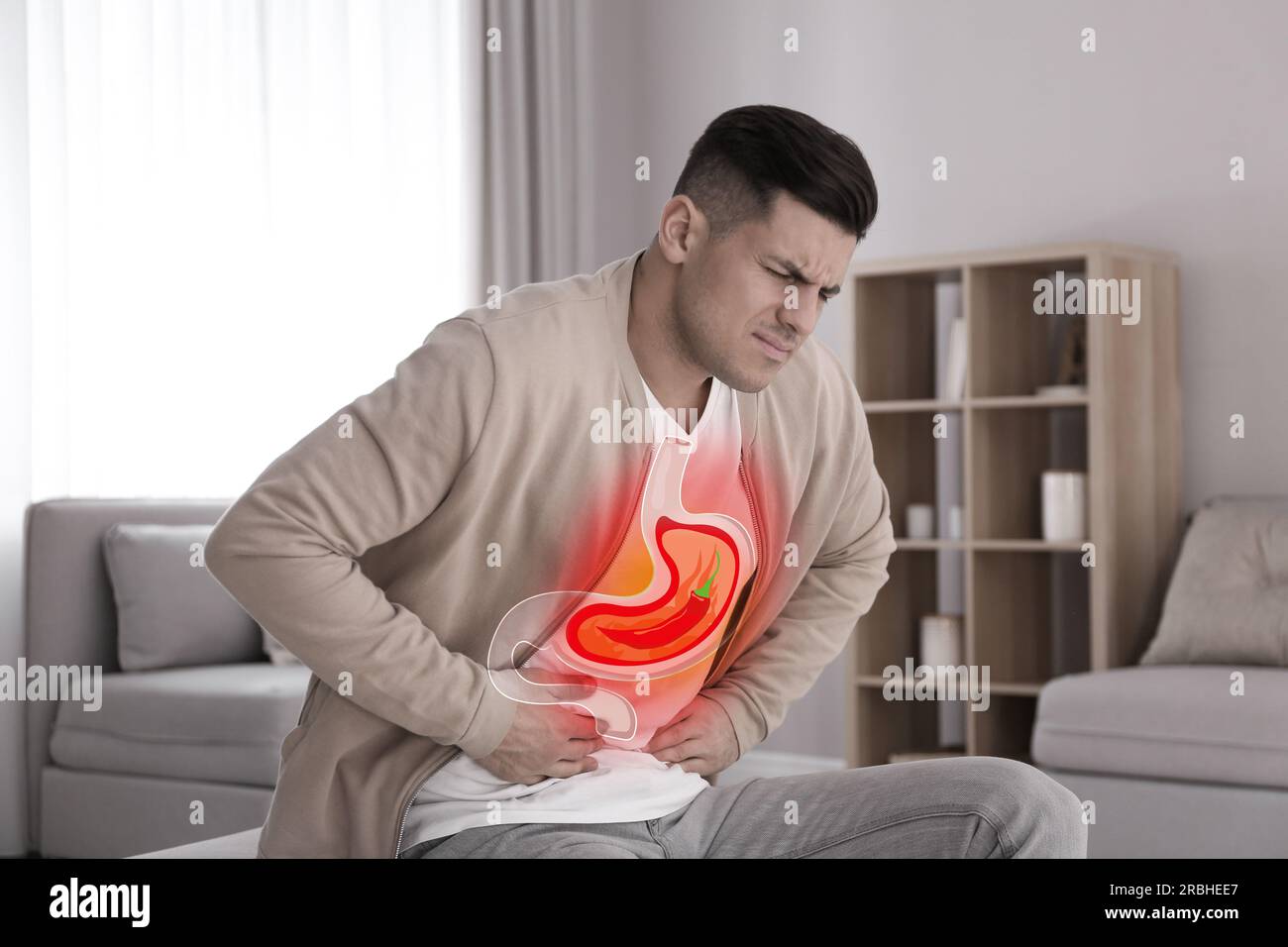 Man suffering from heartburn at home. Stomach with hot chili pepper