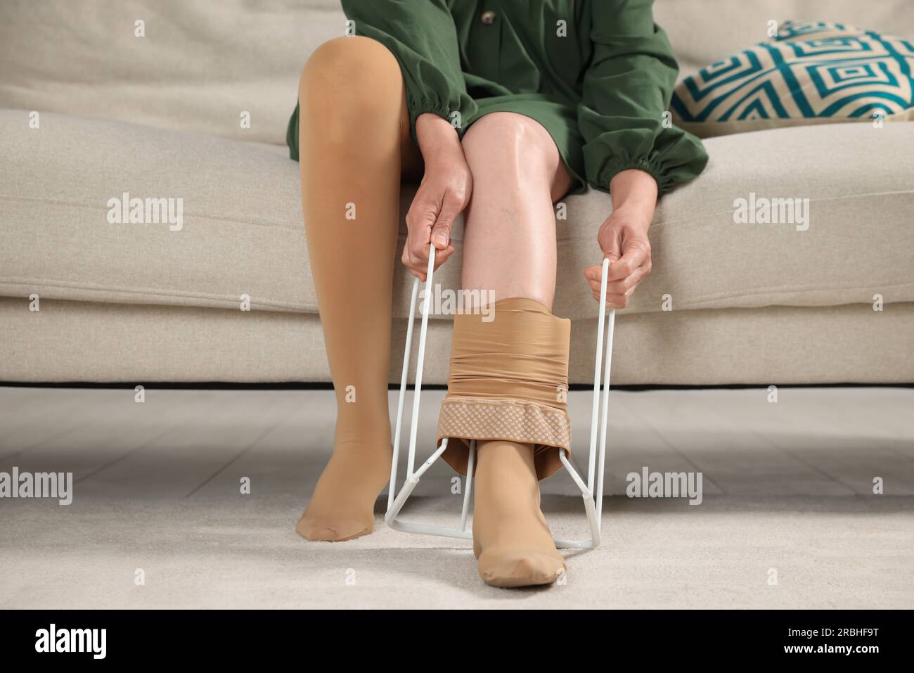 Woman putting on compression tights with stocking donner in living room
