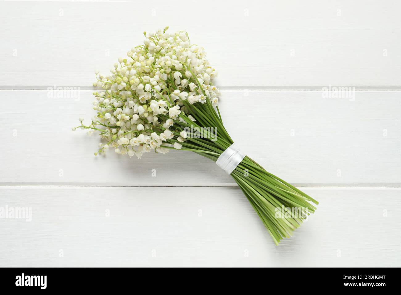 Beautiful lily of the valley bouquet on white wooden table, top view ...