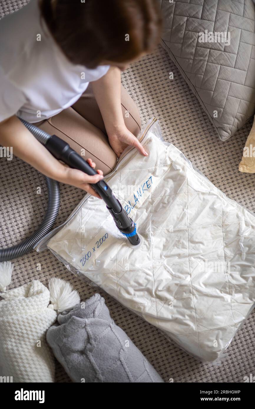 The girl pumps out air with a vacuum cleaner from a vacuum bag with pillow  and blanket. The concept of storage and transportation of clothing, things  Stock Photo - Alamy