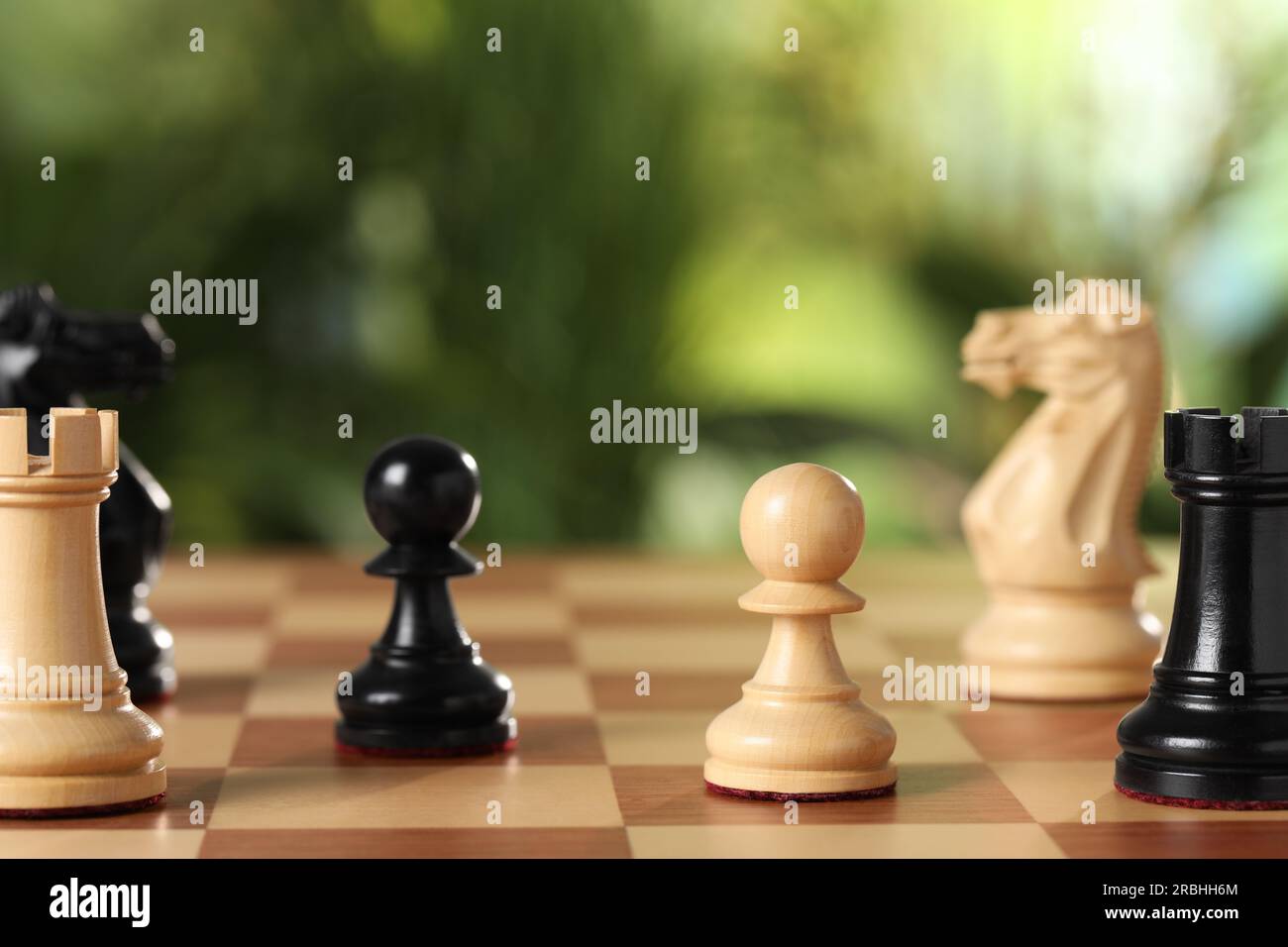 Wooden chess pieces on game board against blurred background, closeup Stock Photo