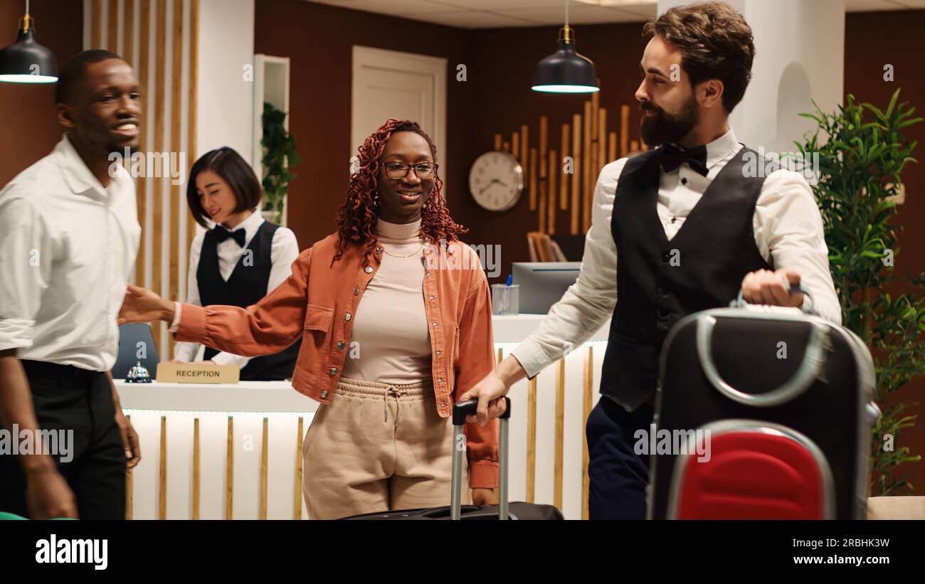 Happy african american tourists tipping helpful bellboy carrying their