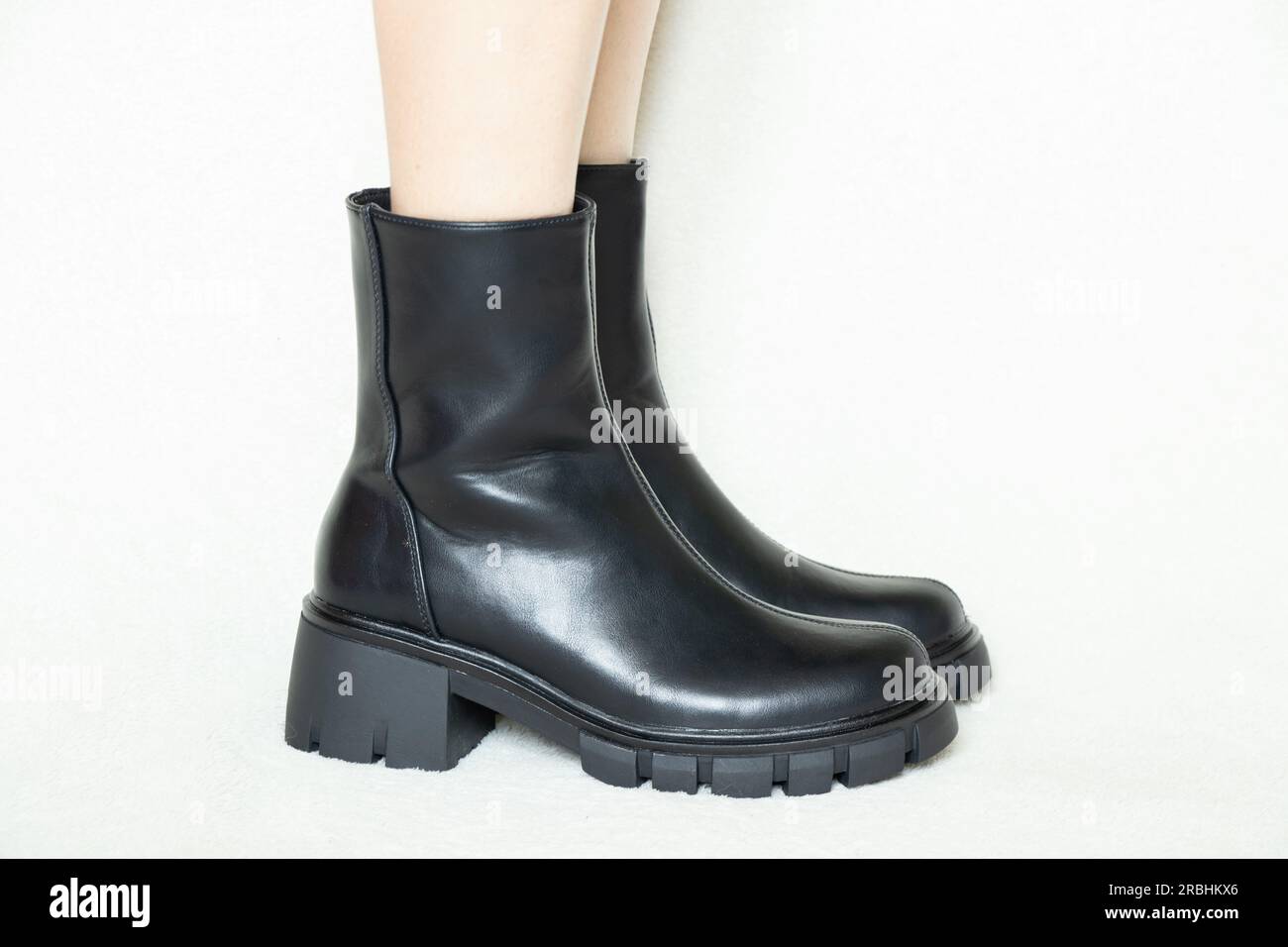 Foot In Boot girl in high black boots on a white background, womens shoes, feet in ...