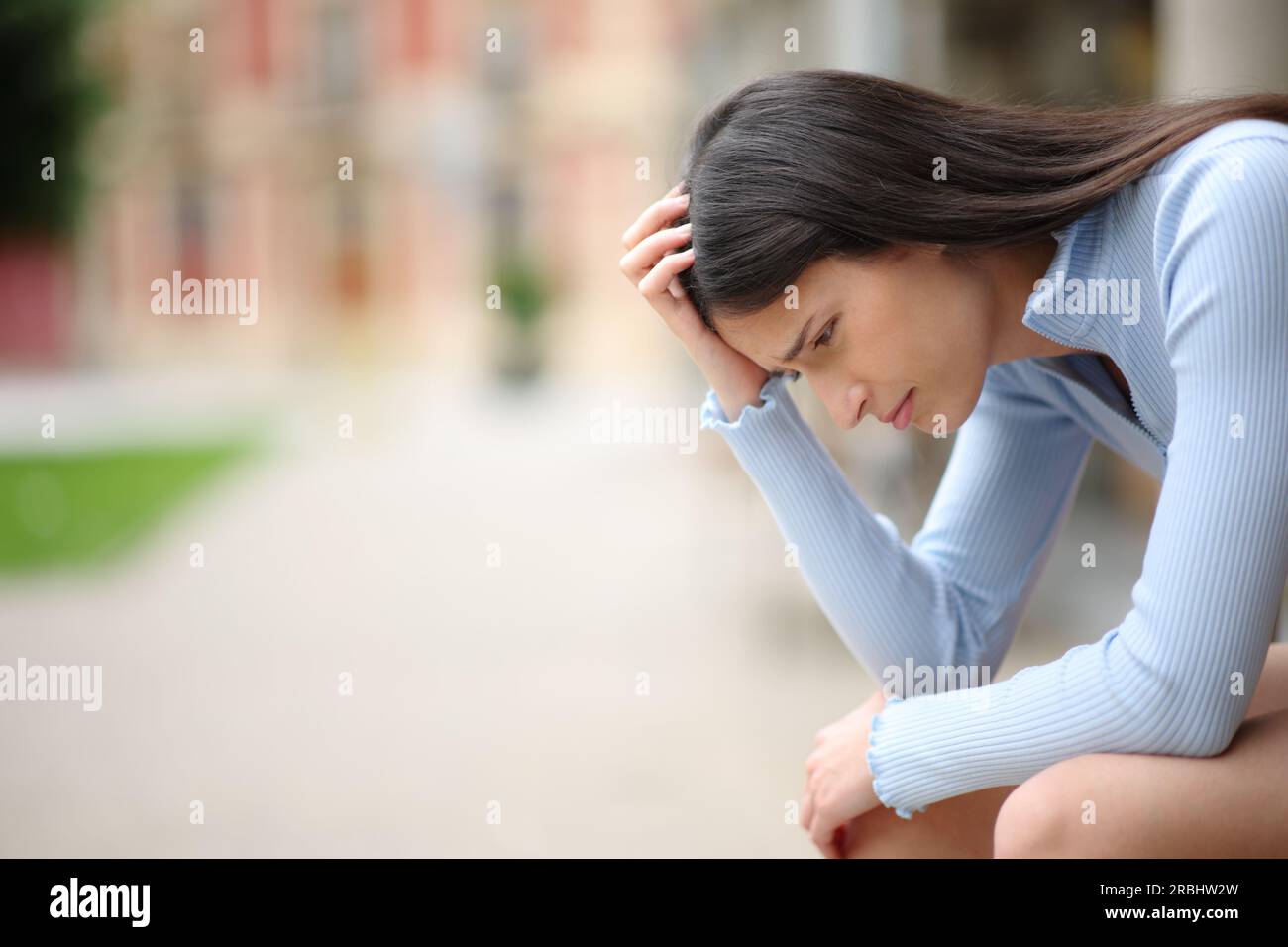 Profile of a sad woman complaining alone in a street Stock Photo