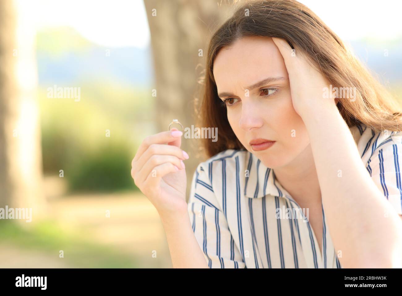 Worried fiancee looking at engagement ring in nature Stock Photo
