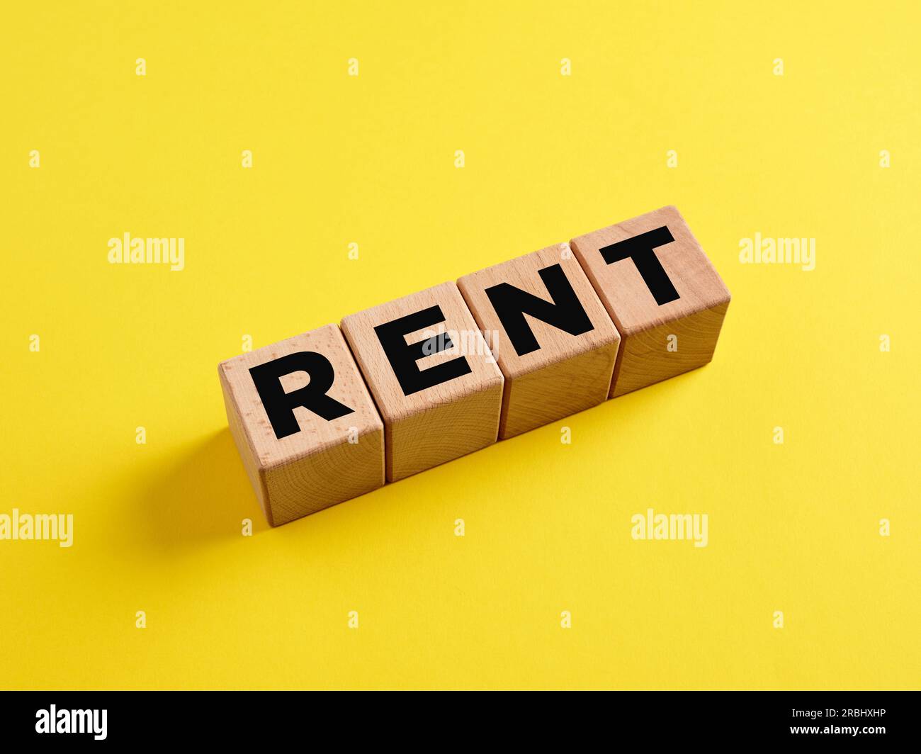 The word Rent on wooden cubes on yellow background. Search for housing for rent or property rental. The concept of renting. Investments. Stock Photo