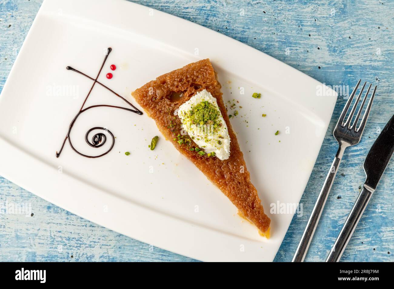 Turkish dessert ekmek kadayifi with milk cream and pistachio on a white