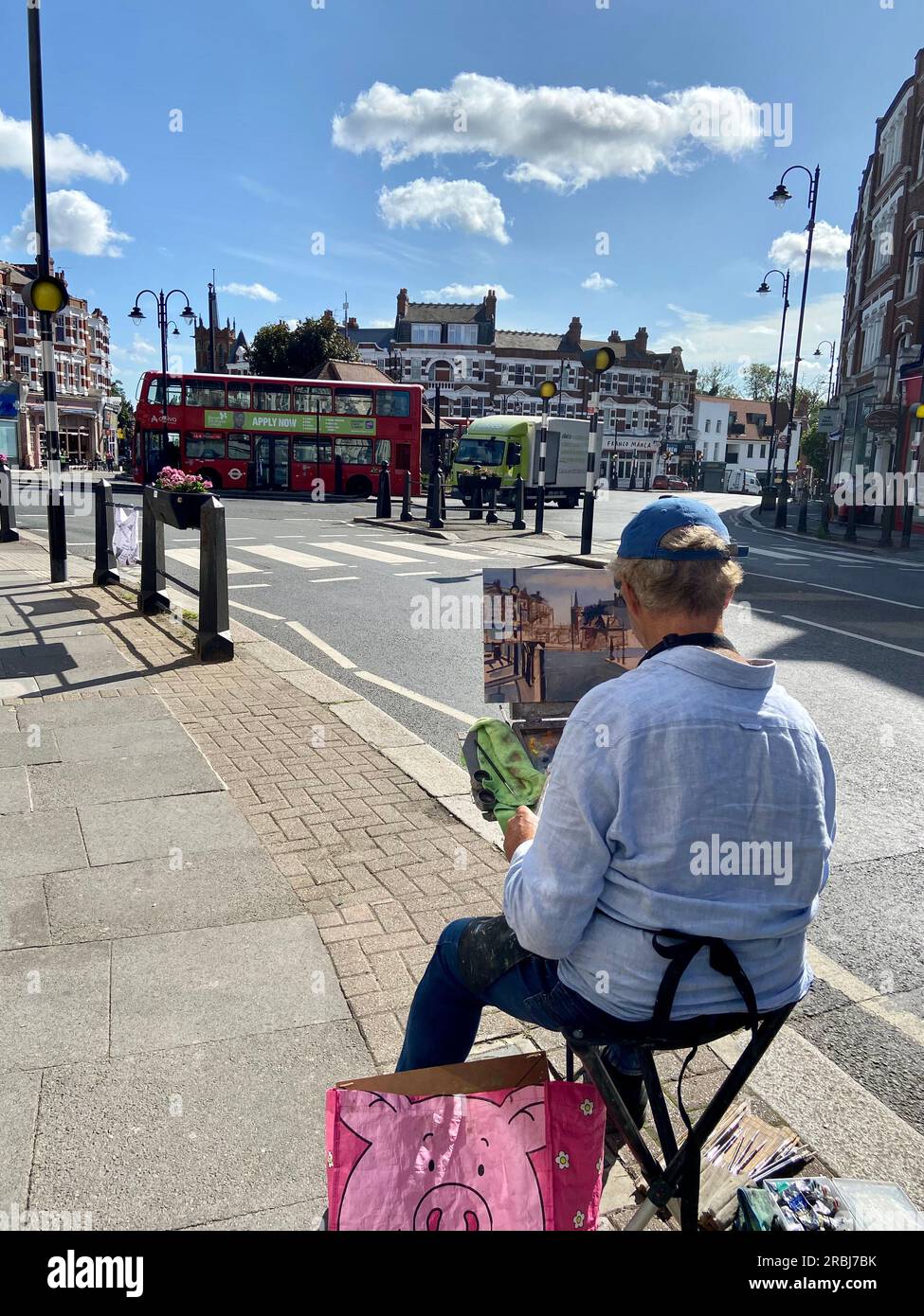 a man sitting on a collapsible chair does a painting of muswell hill broadway in watercolours N10 london england UK Stock Photo