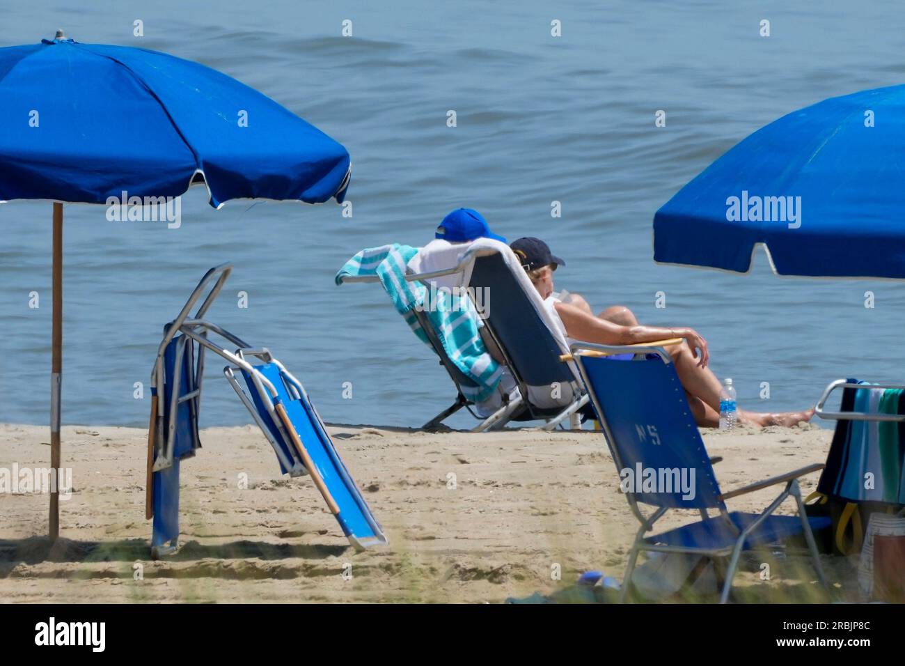 President Joe Biden, in blue hat, sits on the beach with first lady ...