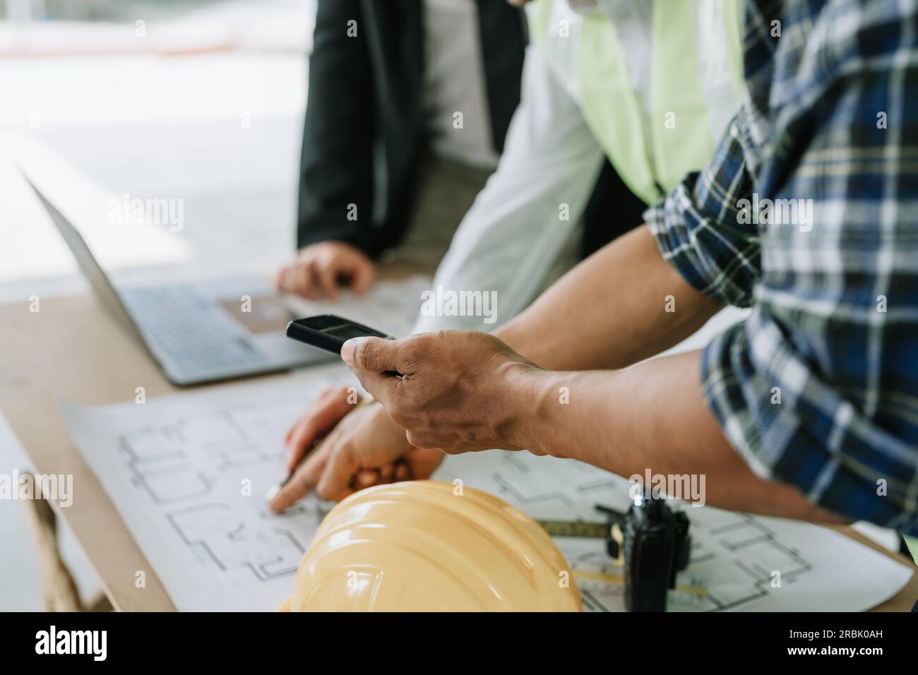 multi ethnic engineer brainstorming and measuring for cost estimating on blueprint and floor