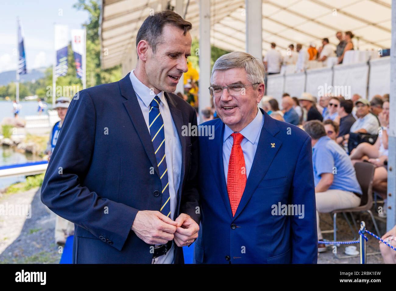 Jean-Christophe Rolland, President of World Rowing, left, speaks with  Thomas Bach, President of the International Olympic Committee (IOC), on the  third day of the 2023 World Rowing Cup at Rotsee lake in