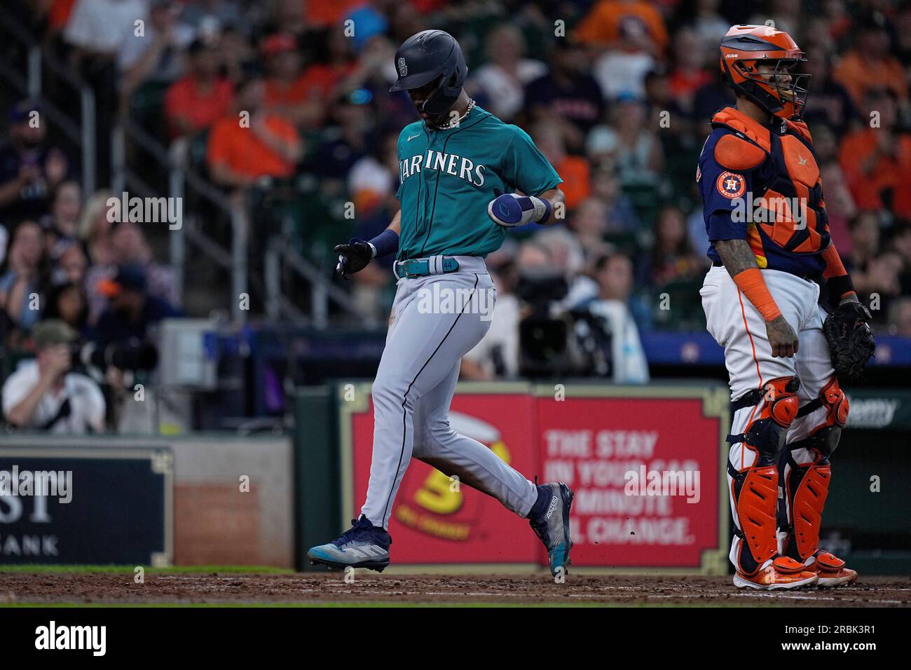Seattle Mariners' Julio Rodriguez, left, scores behind Houston Astros