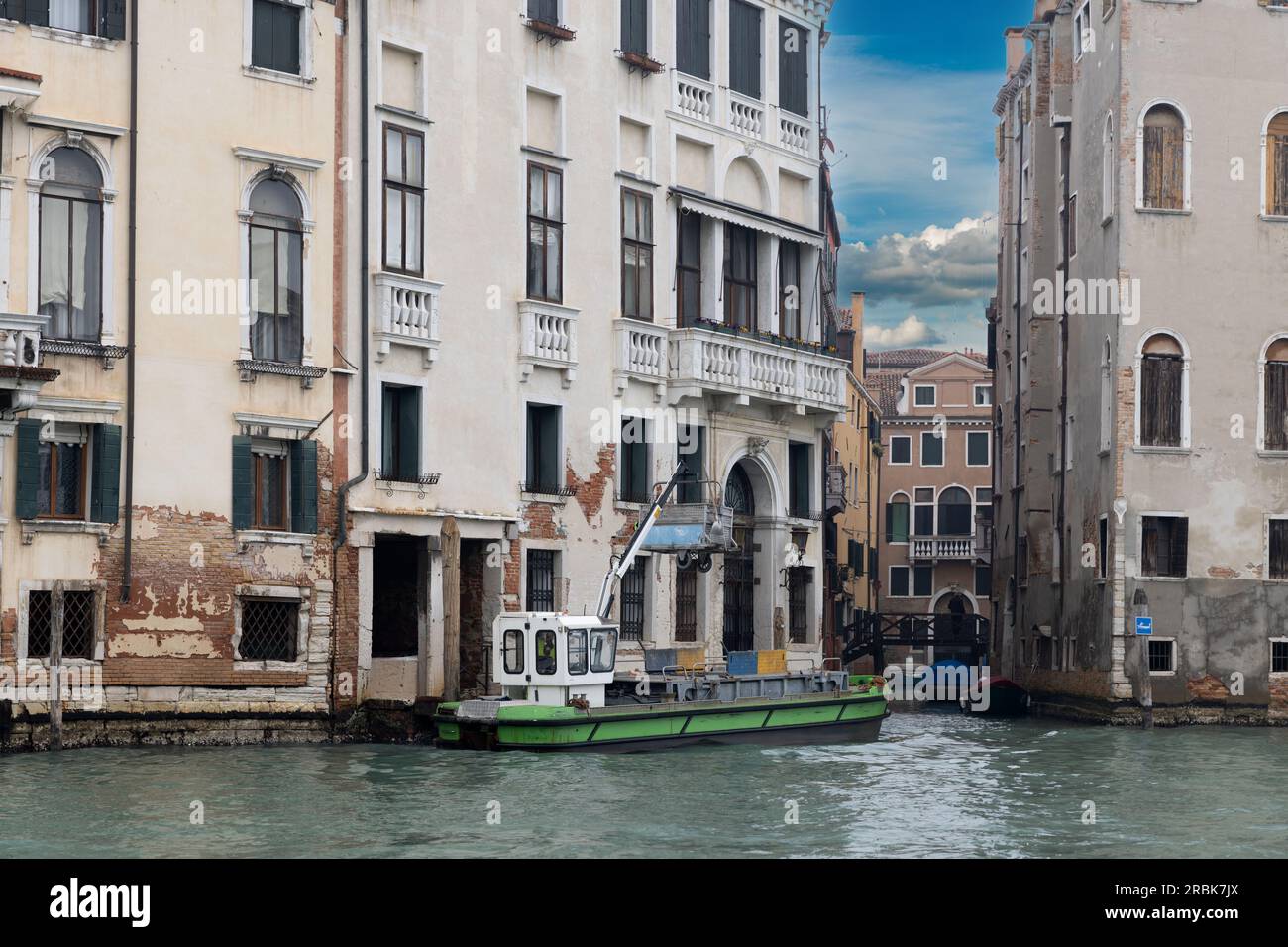 Trash collection at Venice. Buildings on Grand Canal, with waste collection boat. Stock Photo
