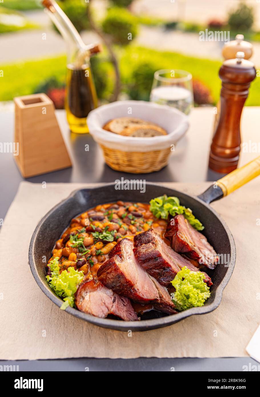 Bean stew with smoked and roasted pork hock slice on restaurant table Stock Photo