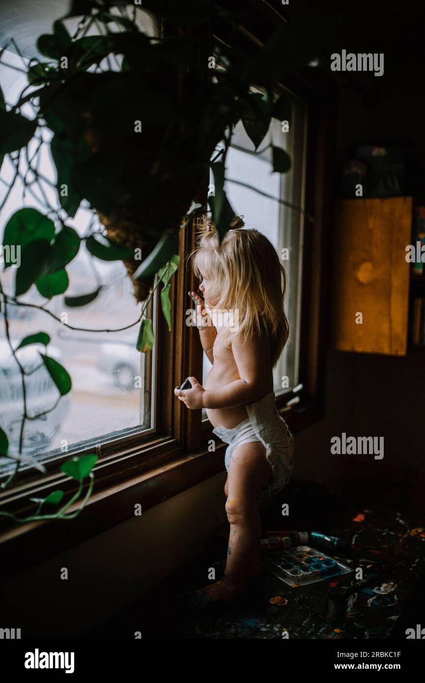 Toddler looking out of window Stock Photo