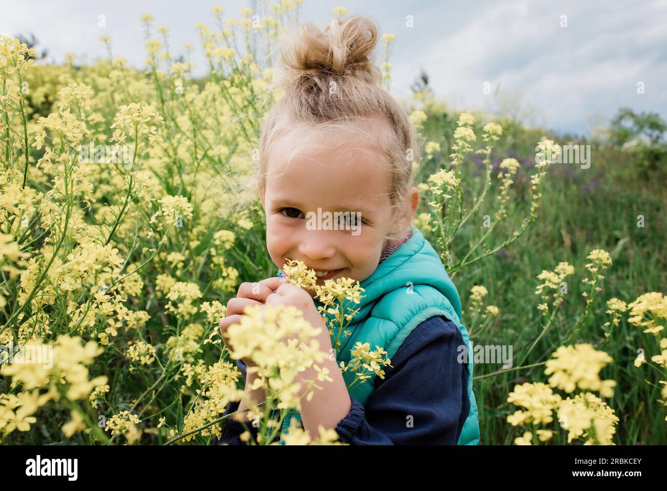 portrait of a young girl sat in a field of yellow flowers smiling Stock ...