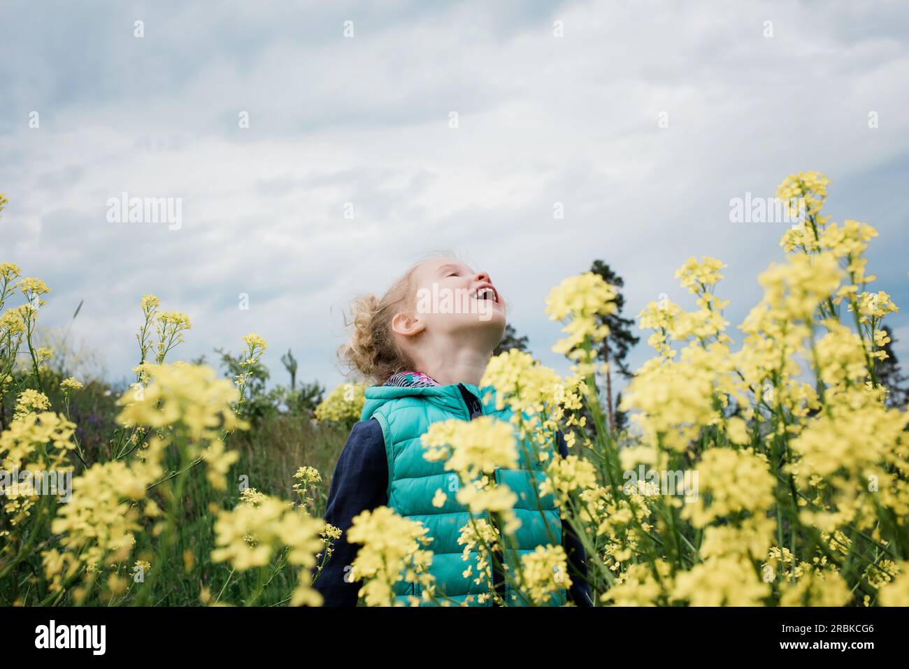 young girl standing in a field of flowers looking up to the sky