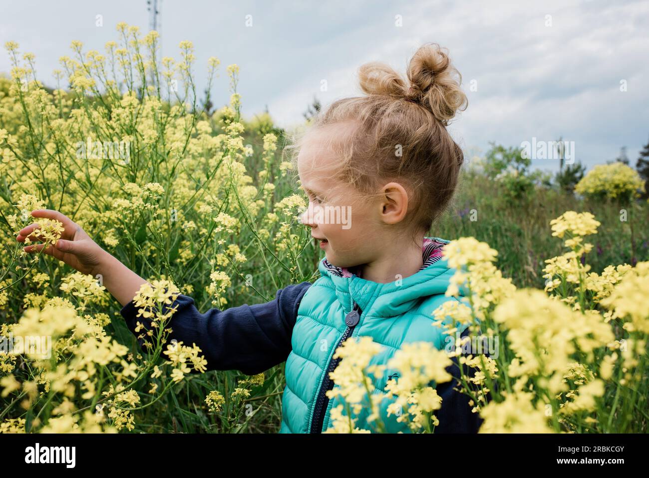 young girl sat in a field of flowers looking happy Stock Photo - Alamy