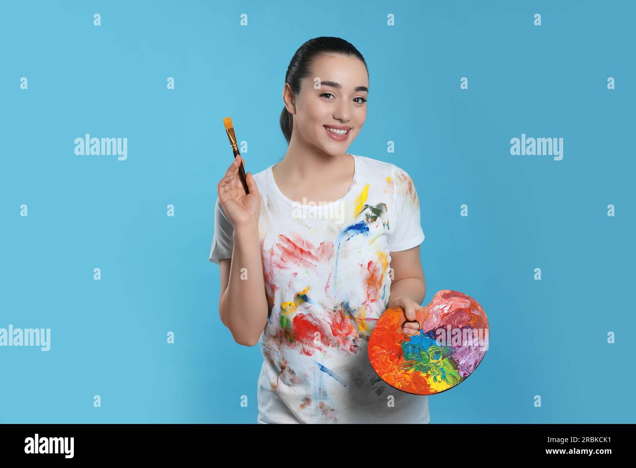 Woman with painting tools on light blue background. Young artist Stock ...