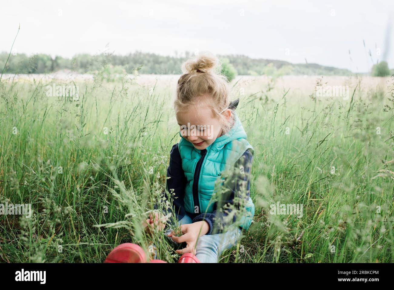 young girl sitting in a field smiling and happy Stock Photo - Alamy
