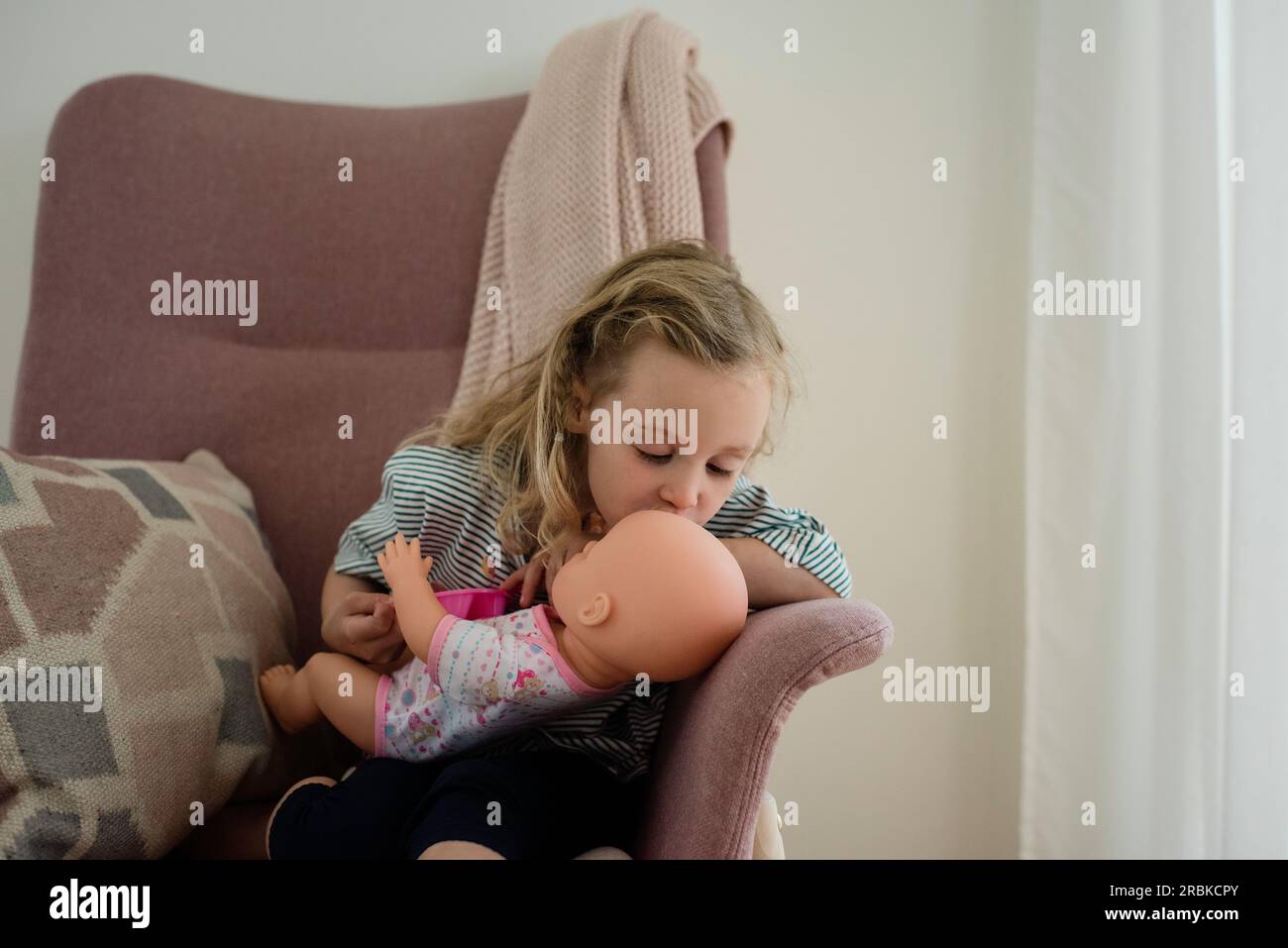 young girl kissing her dolls head Stock Photo Alamy