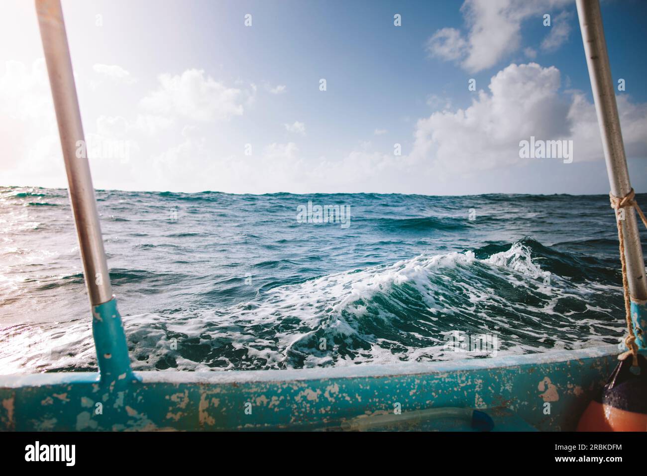 A small wave out at sea is framed by a deep sea fishing boath on Stock Photo