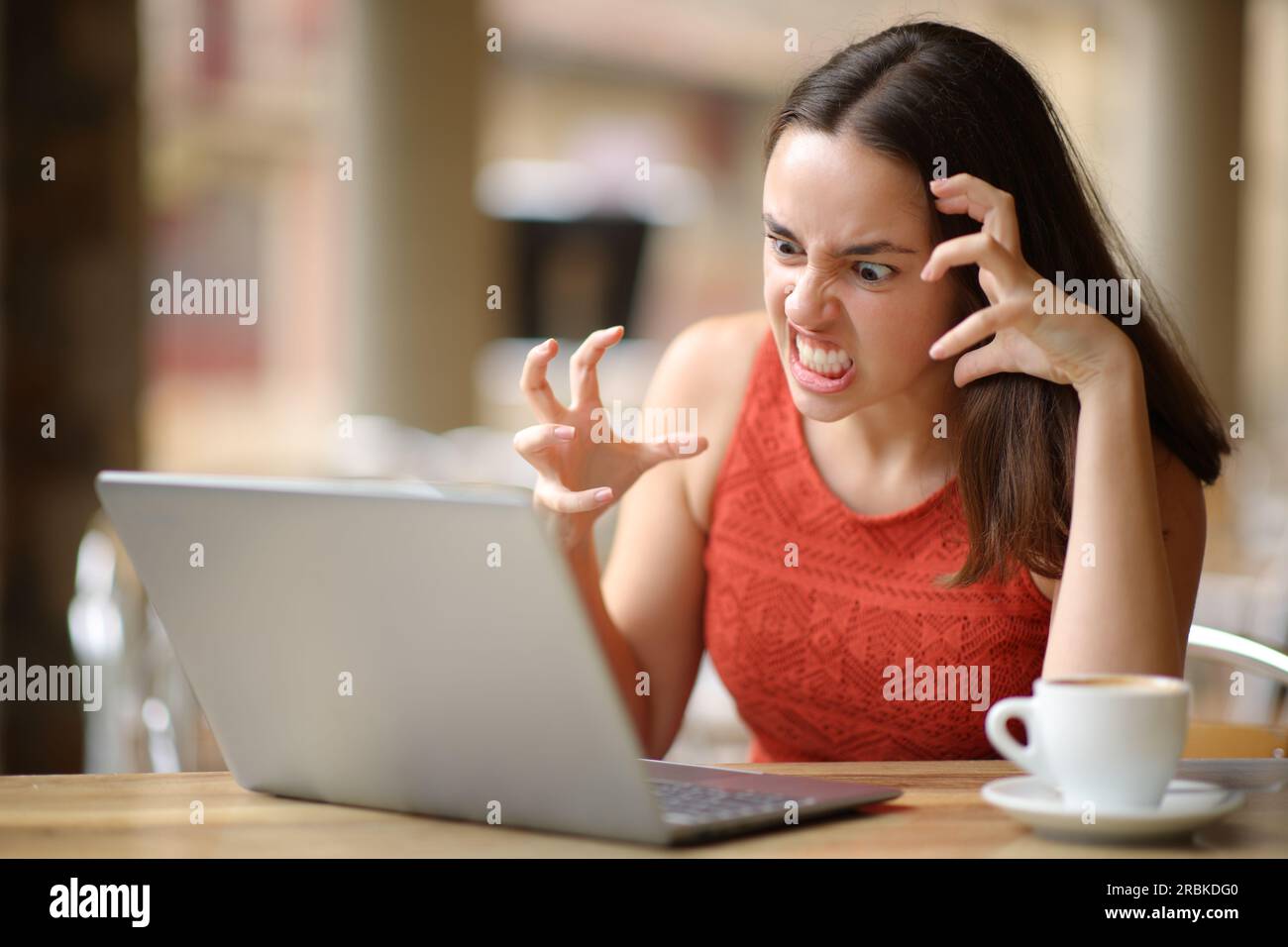 Angry woman having problems with a laptop in a bar terrace Stock Photo