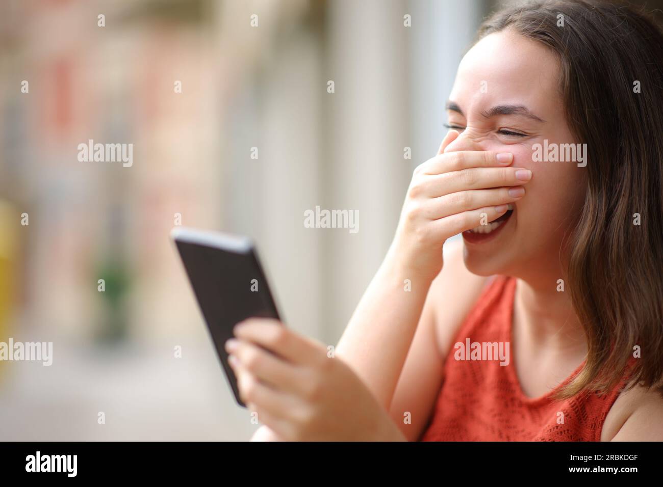 Happy woman laughing loud checking cell phone in the street Stock Photo