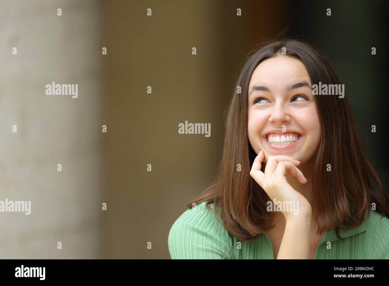 Front view of a happy woman looking at side wondering in the street Stock Photo
