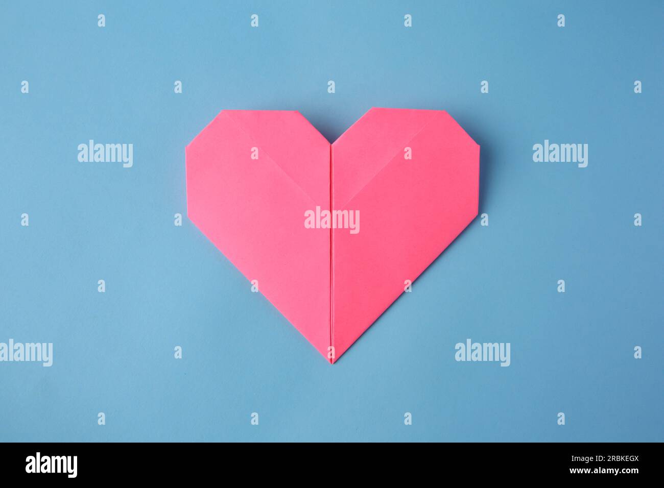 Origami art. Handmade pink paper heart on light blue background, top ...