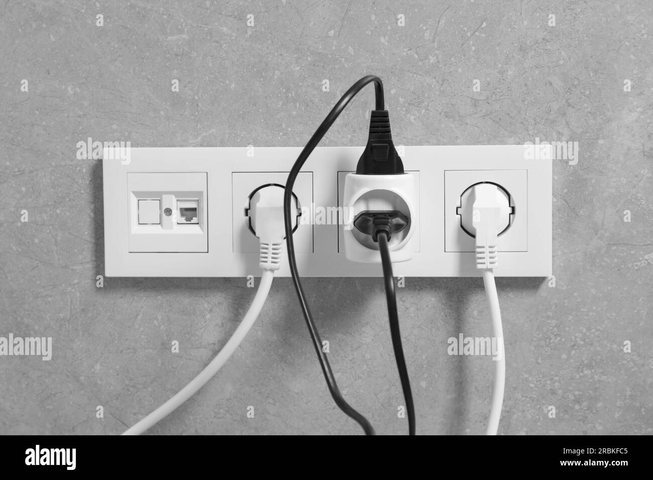 Many different electrical power plugs in sockets on grey wall Stock