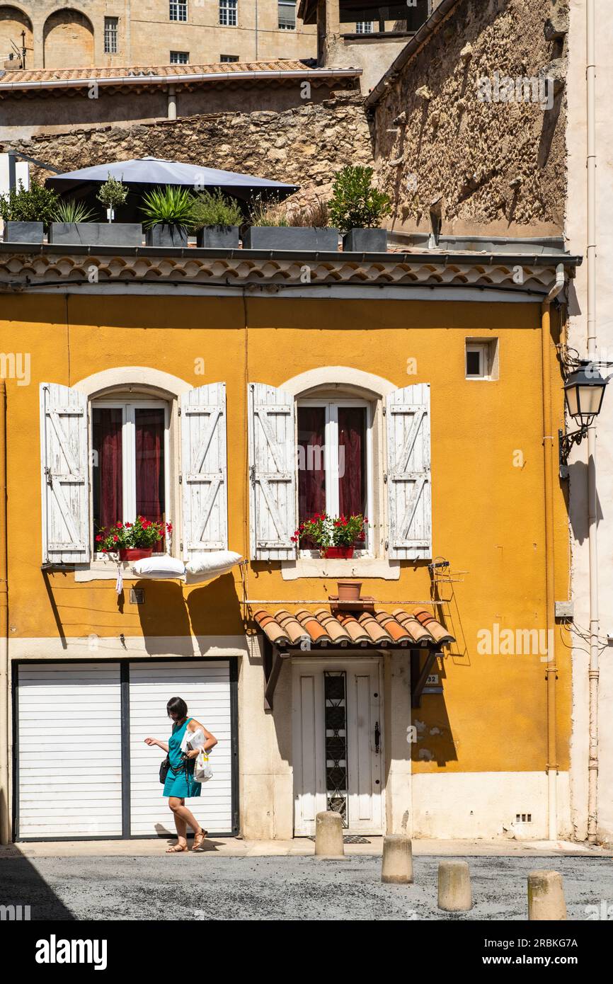 Woman walking past a yellow house in the old town, Béziers, Hérault, France, Europe Stock Photo