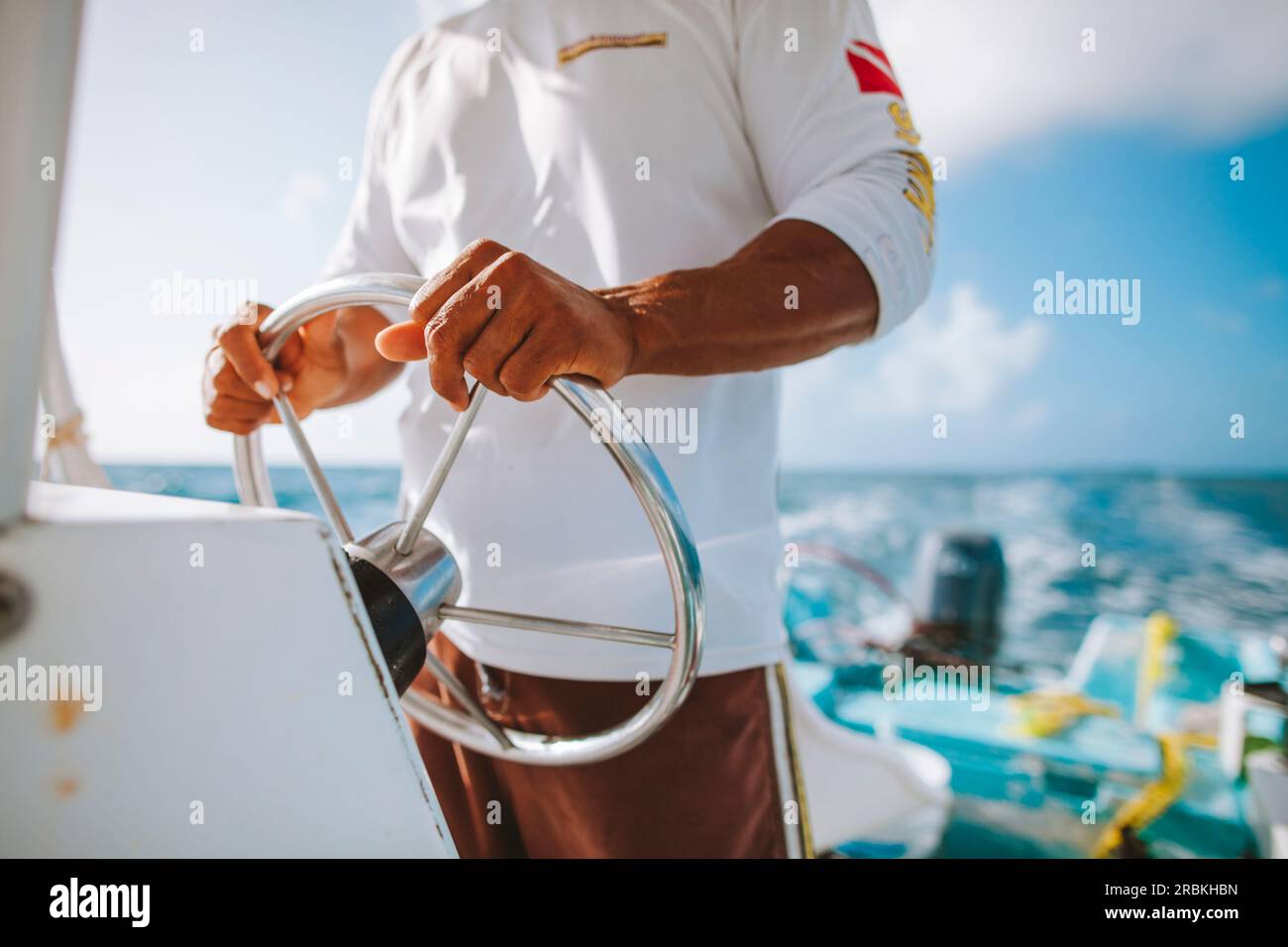 The captain of small fishing boat steers his ship on a sunny mor Stock