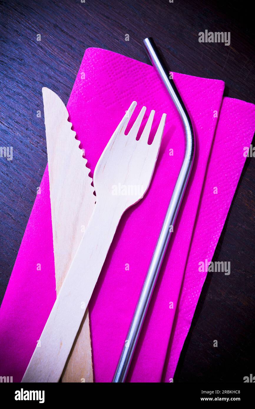 Eco-friendly drinking straw and wooden cutlery on pink napkin Stock Photo