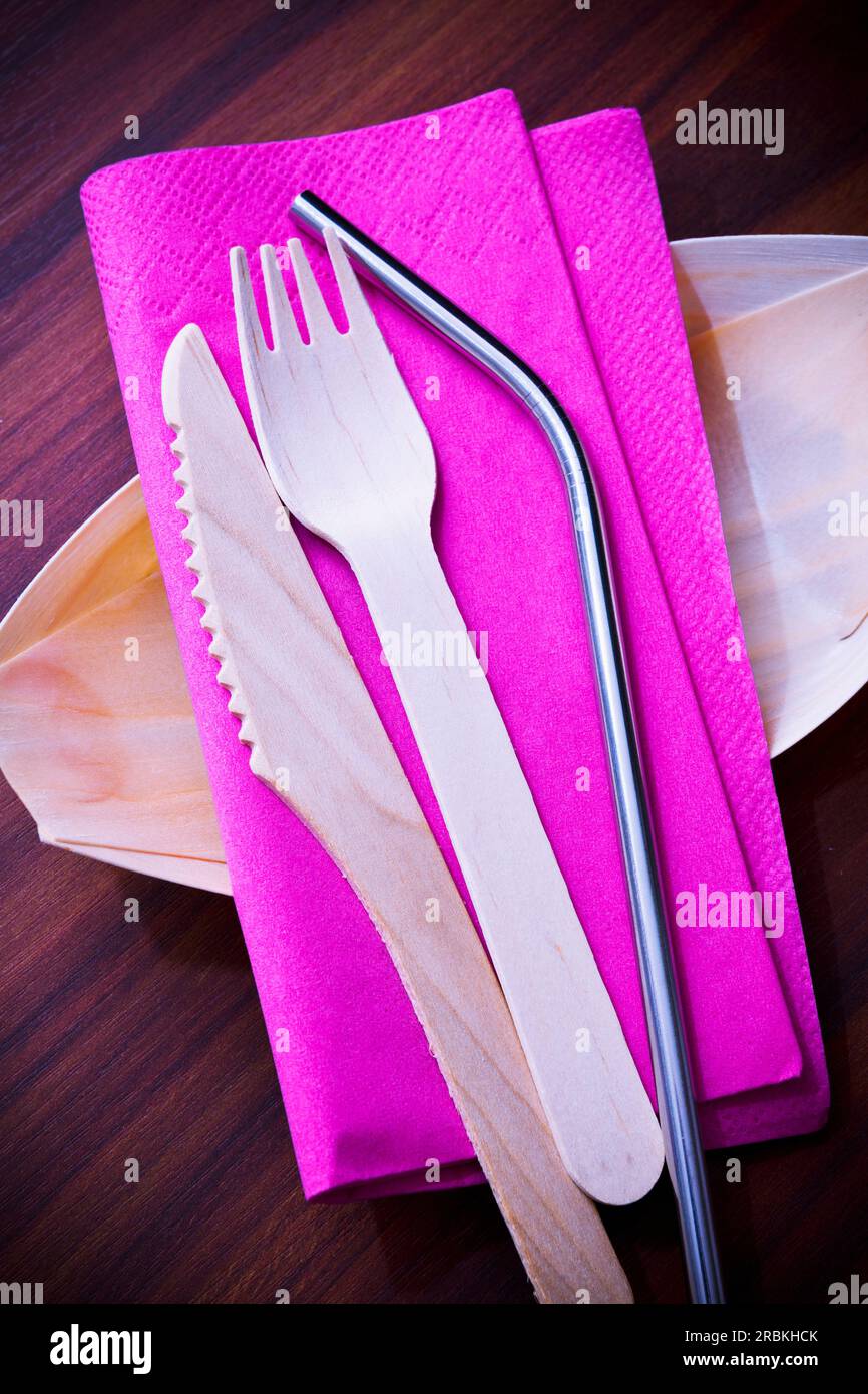 Eco-friendly drinking straw and wooden cutlery on pink napkin Stock Photo