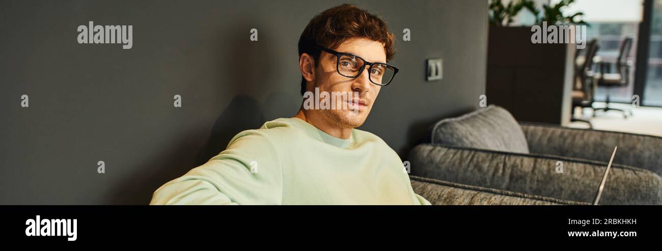 portrait of stylish businessman in casual clothes and eyeglasses looking at camera in contemporary office environment, professional headshot, confiden Stock Photo