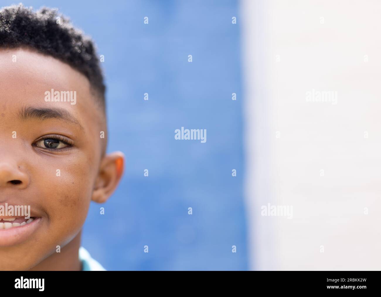 Half face portrait of smiling african american boy in elementary school playground, copy space. Education, inclusivity, elementary school and learning Stock Photo