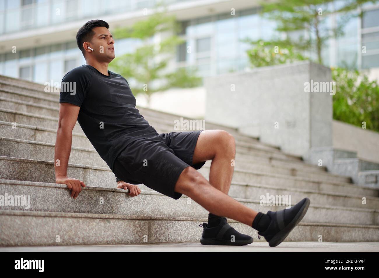 Sportsman listening to music in earbuds when doing dips focusing on triceps Stock Photo