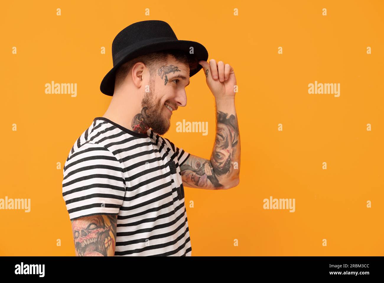 Smiling hipster man wearing stylish hat on orange background. Space for text Stock Photo