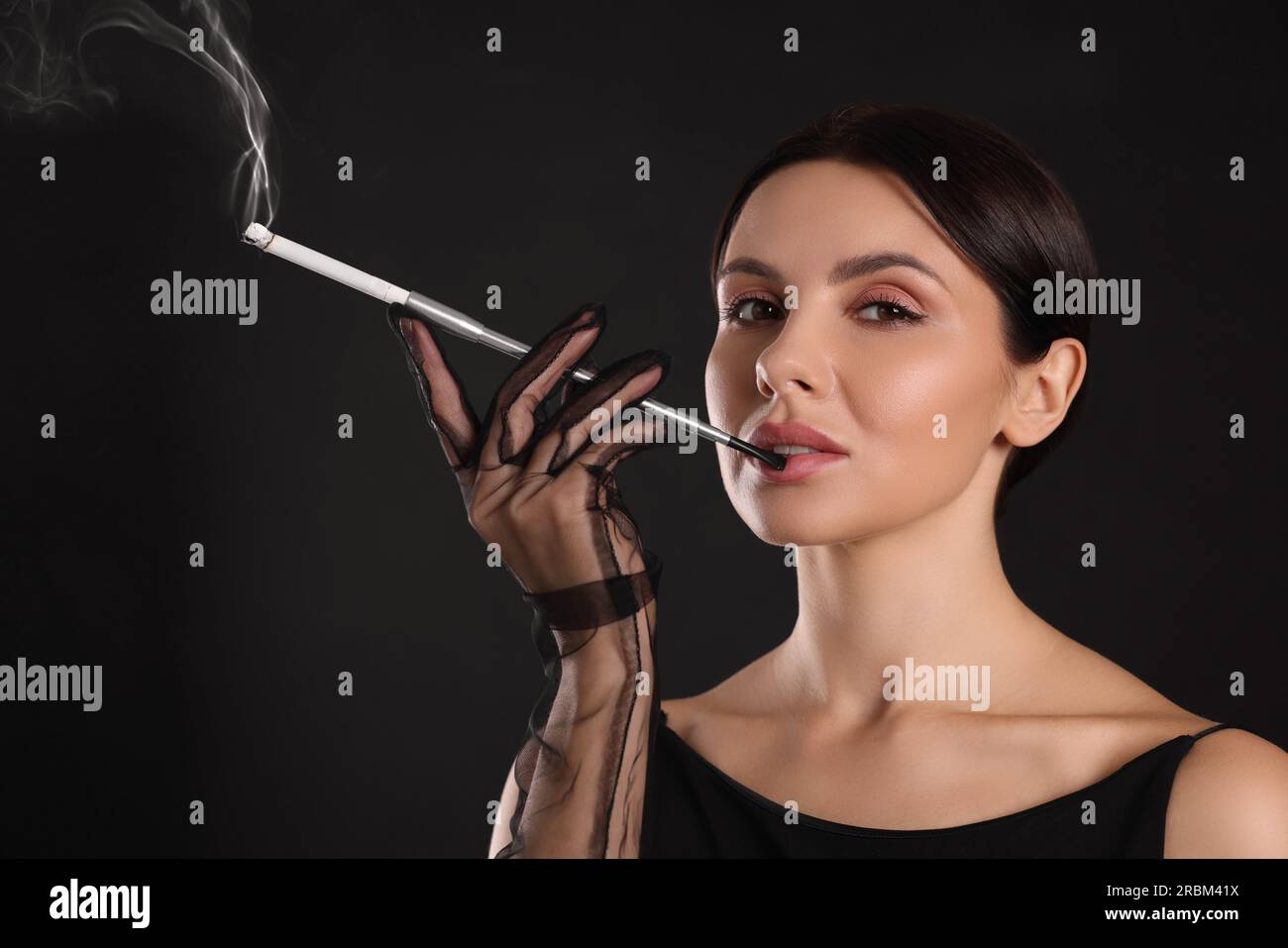 cigarette smoking holder Woman using long cigarette holder for smoking on black background Stock  Photo