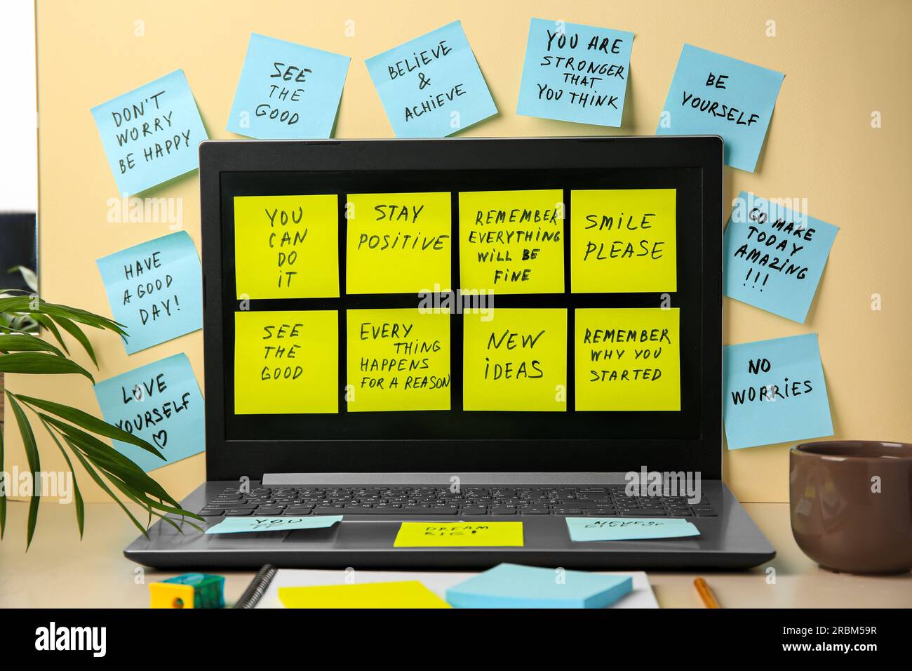 Paper notes with life-affirming phrases and laptop on table against beige background Stock Photo