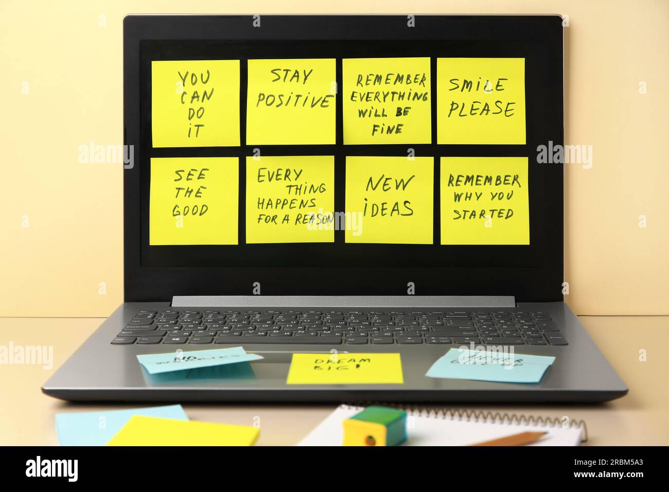 Paper notes with life-affirming phrases and laptop on table against beige background Stock Photo
