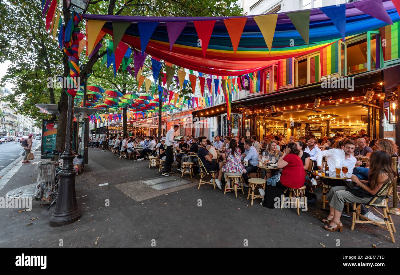 Romantic Paris. People enjoy outside dining at restaurants with PRIDE, LGBTQ+ decorations in Rue des Archives, Paris. Stock Photo