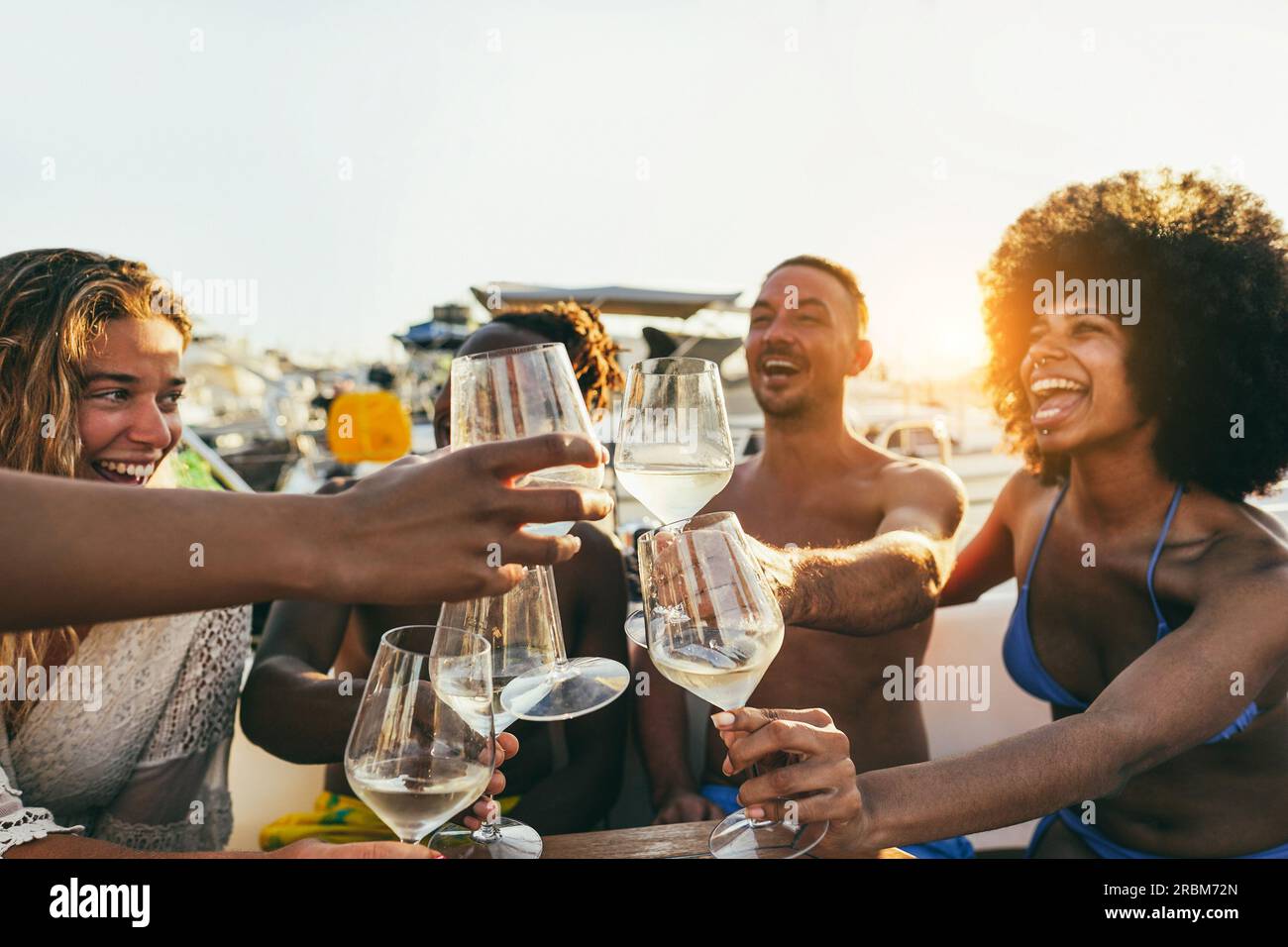 Multiracial people having fun cheering with wine at boat party outdoor - Focus on right glasses Stock Photo