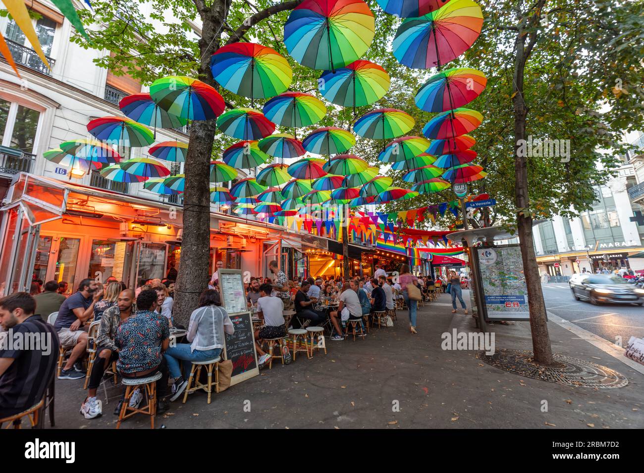 Romantic Paris. People enjoy outside dining at restaurants with PRIDE, LGBTQ+ decorations in Rue des Archives, Paris. Stock Photo