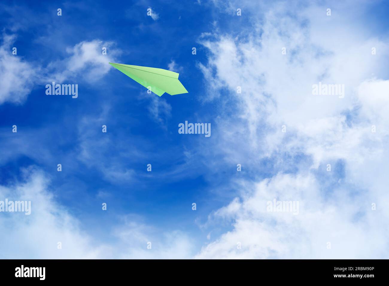 White clouds and paper airplane flying in blue sky on sunny day. Space ...