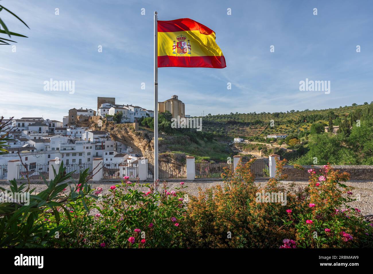 Flag of Spain and Setenil de las Bodegas Skyline - Setenil de las Bodegas, Andalusia, Spain Stock Photo