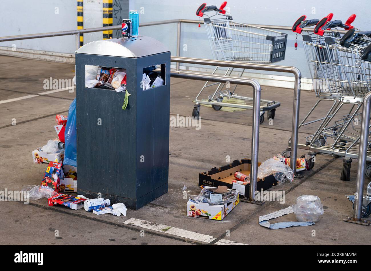 Overflowing dumpster, trash can with plastic bags and cardboard, filthy